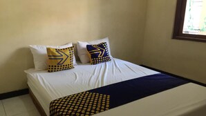 Ein Bett mit weißer Bettwäsche und zwei dekorativen Kissen mit geometrischen Mustern.