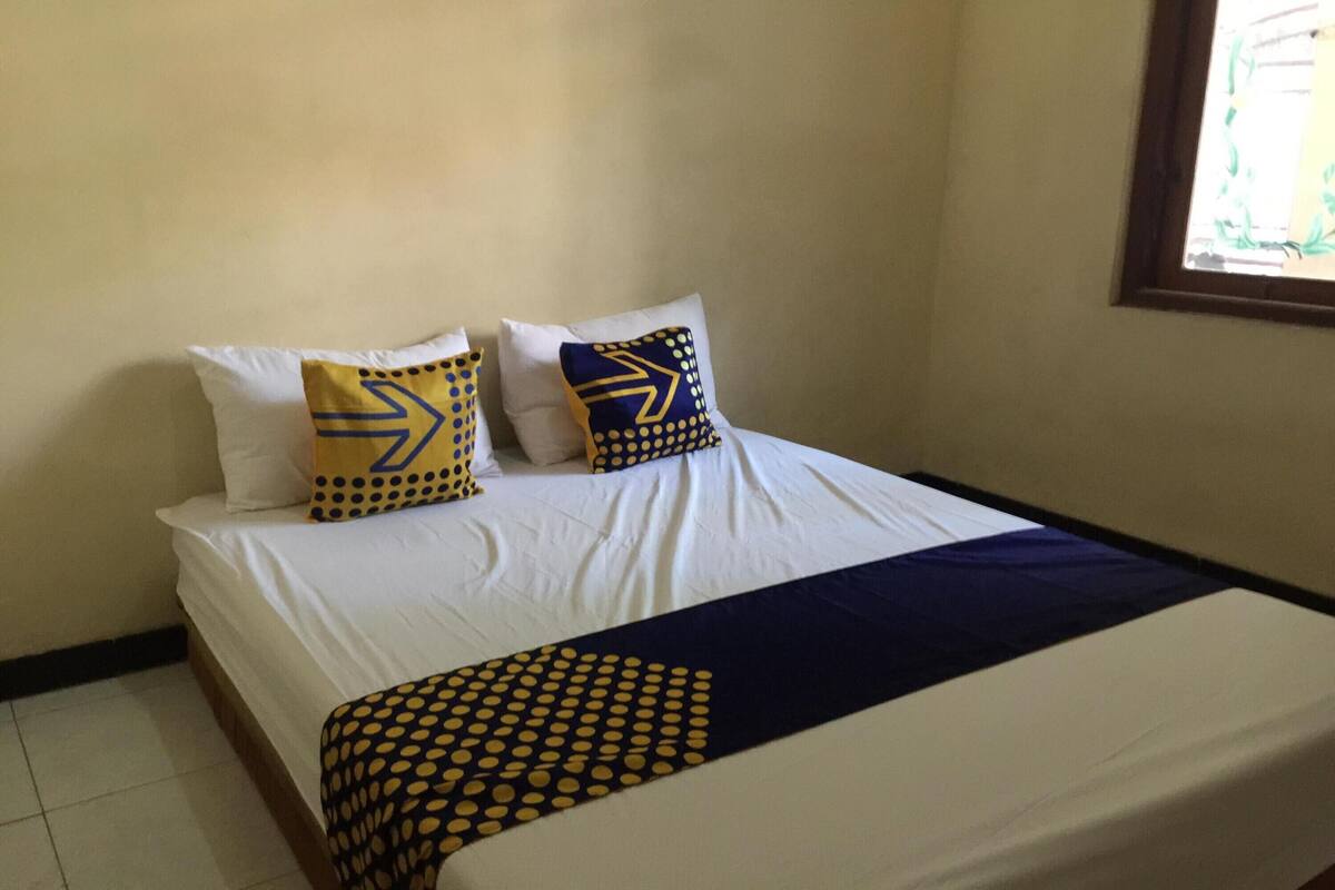 Una cama con ropa de cama blanca y dos almohadas decorativas con diseños geométricos.