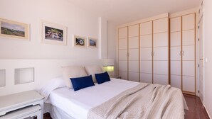 Quarto com cama, mesas de cabeceira, guarda-roupa e quadros nas paredes.
