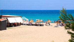 Une plage avec des parasols, des chaises longues et une vue dégagée sur l’océan.