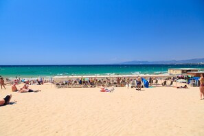 A beach with people sunbathing and swimming.