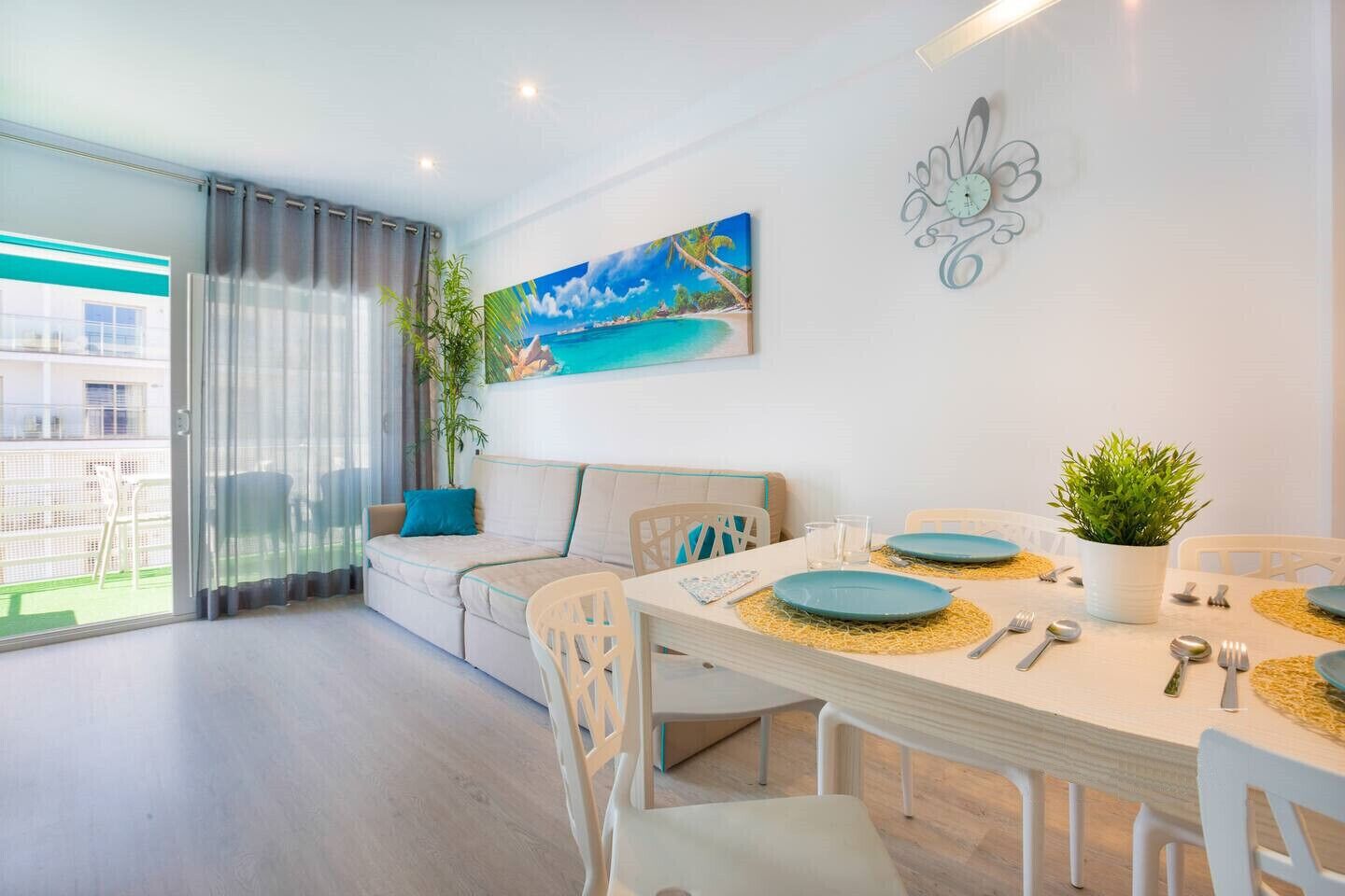 Ein modernes Wohnzimmer mit Essbereich, einer Couch, einem Gemälde und einer Wanduhr.