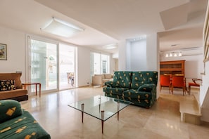Relax and socialize in this spacious living area with a comfortable sofa, dining table, and sliding glass doors leading to the outdoors.