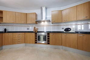 Kitchen features an oven, stainless steel range hood, and wooden cabinets with silver handles.