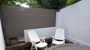 A small outdoor area with two white plastic chairs, a small round table, and a grey inflatable pool. - Maisonnette Rustique (Le Garn)