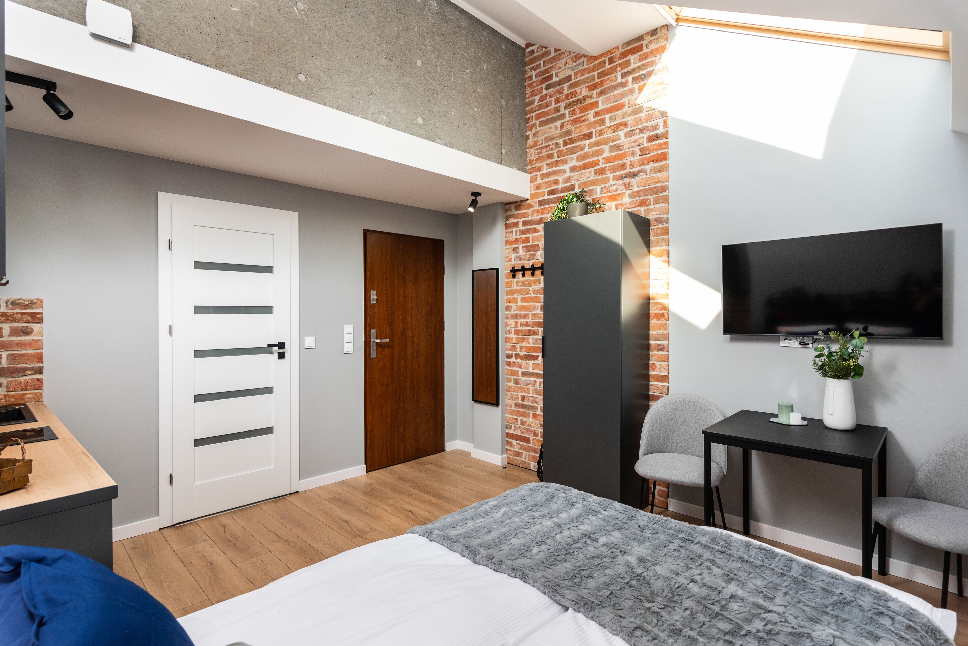 Un dormitorio moderno con zona de altillo, televisor de pantalla plana, escritorio y área de descanso.