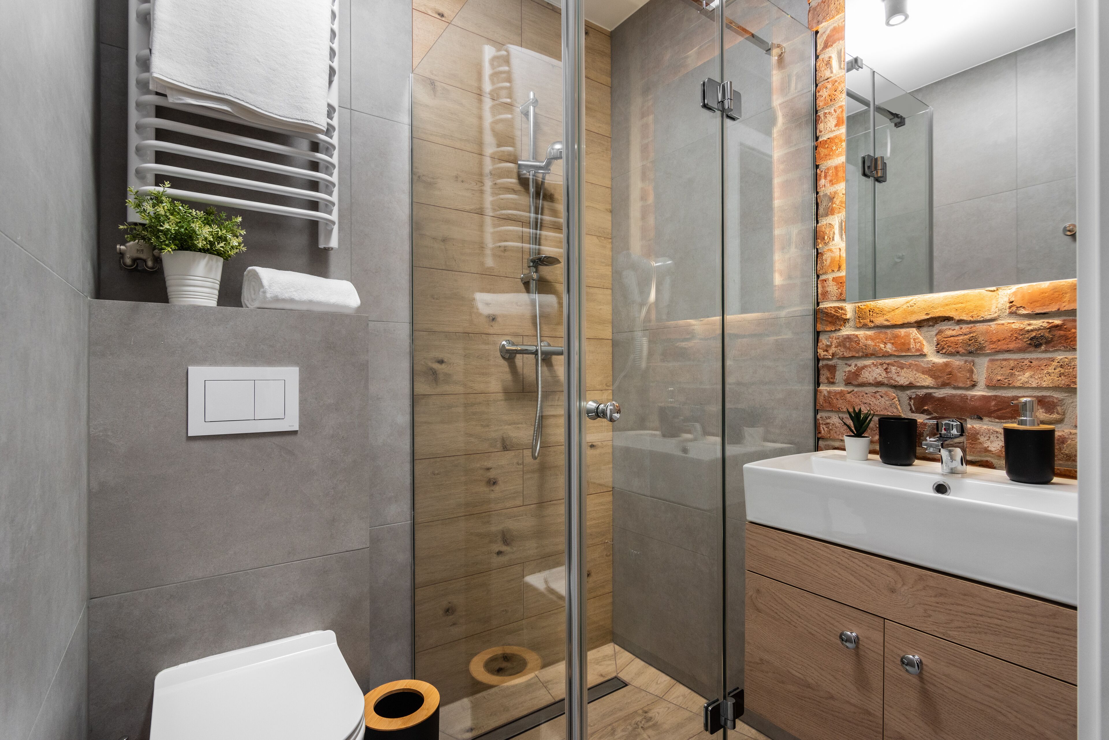 A modern bathroom with a glass shower enclosure, a white sink, and a wooden vanity.