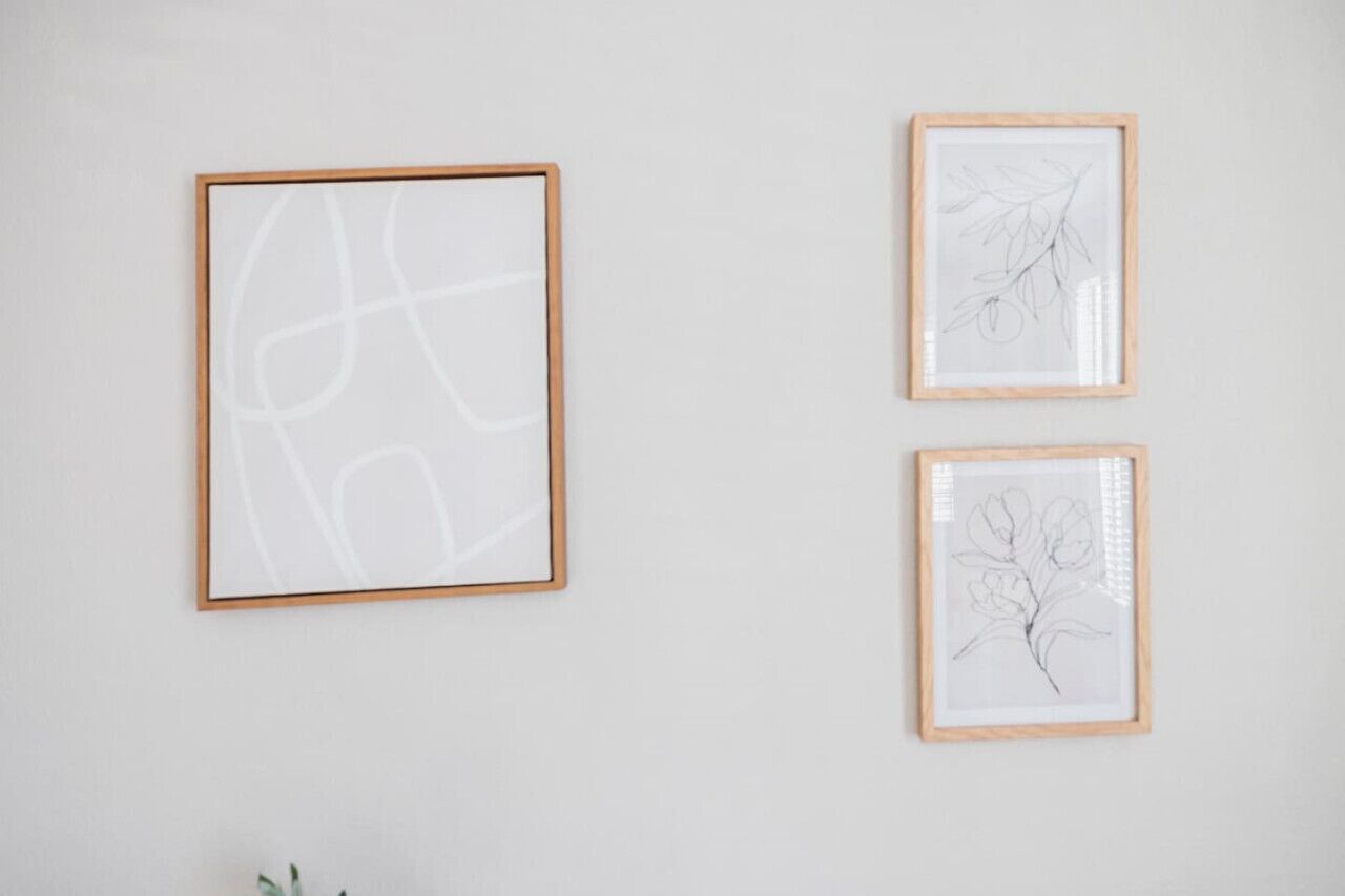 Drei gerahmte Kunstwerke an einer schlichten Wand.