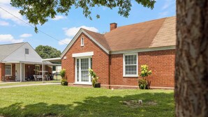A single-story brick house with a covered porch, a well-maintained lawn, and a clear sky.
