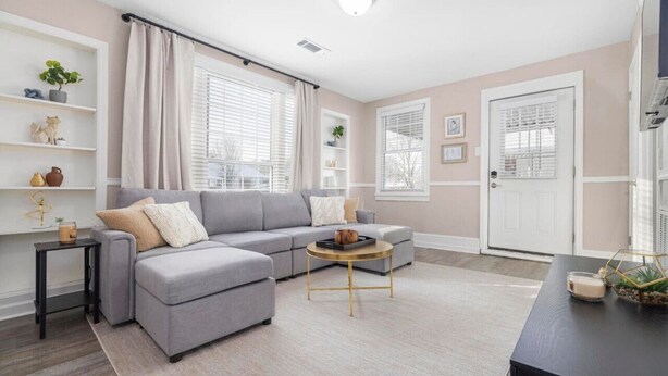 A living room with a grey sectional sofa, a round coffee table, and a bookshelf.