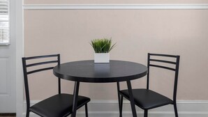 A round table with two black chairs and a potted plant in the center.