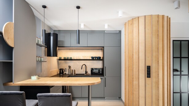 A modern kitchen with grey cabinets, a wooden table, and two grey chairs. - Kalwaryjska Apartments (Kraków)