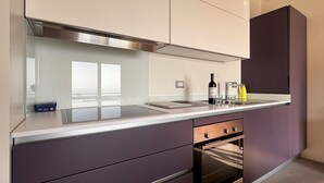 Una cocina moderna con campana de acero inoxidable, horno empotrado y un amplio ventanal que proporciona luz natural.