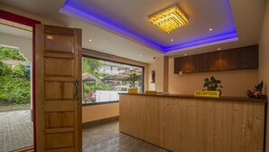 Un mostrador de recepción con detalles de madera, un cartel de recepción y un ventanal con vistas al exterior.