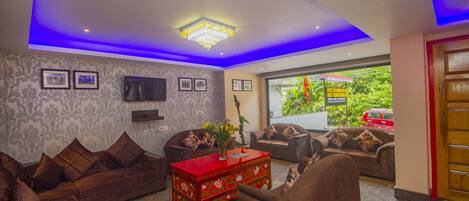 A modern living room with sofas, a red coffee table, and a TV mounted on the wall.