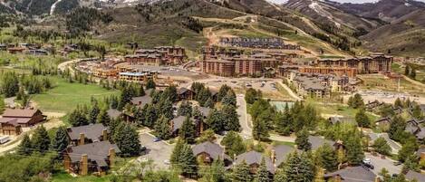 A resort with multiple buildings, a golf course, and mountainous terrain in the background.