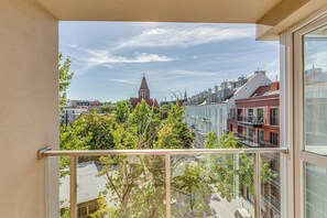 A balcony with a view of a cityscape, including buildings and a church tower.