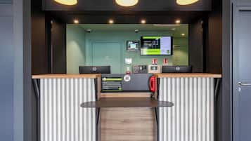 Una reception con una scrivania, un computer, un telefono e un monitor che mostra un menu.