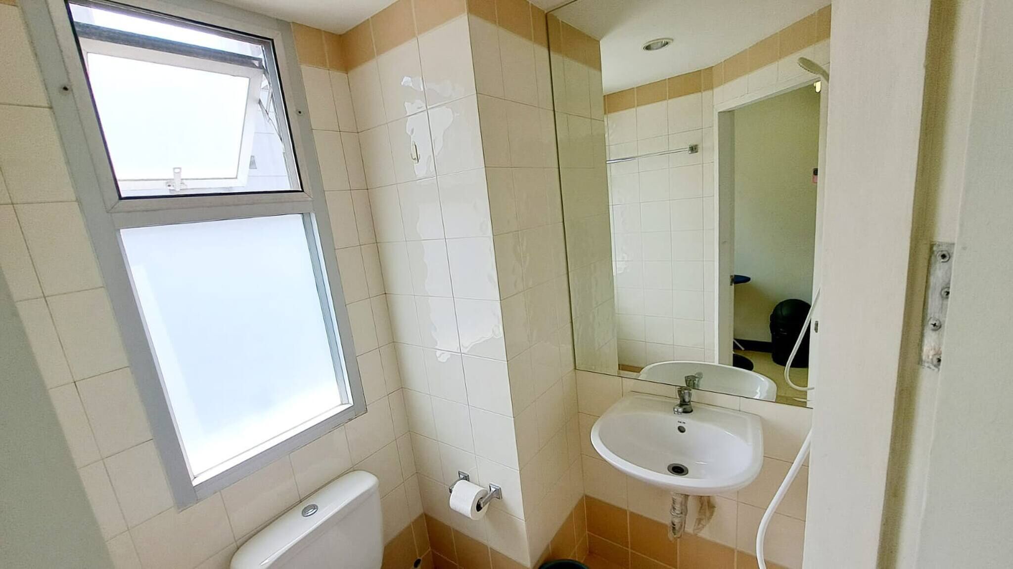 A small bathroom with a toilet, sink, and mirror.
