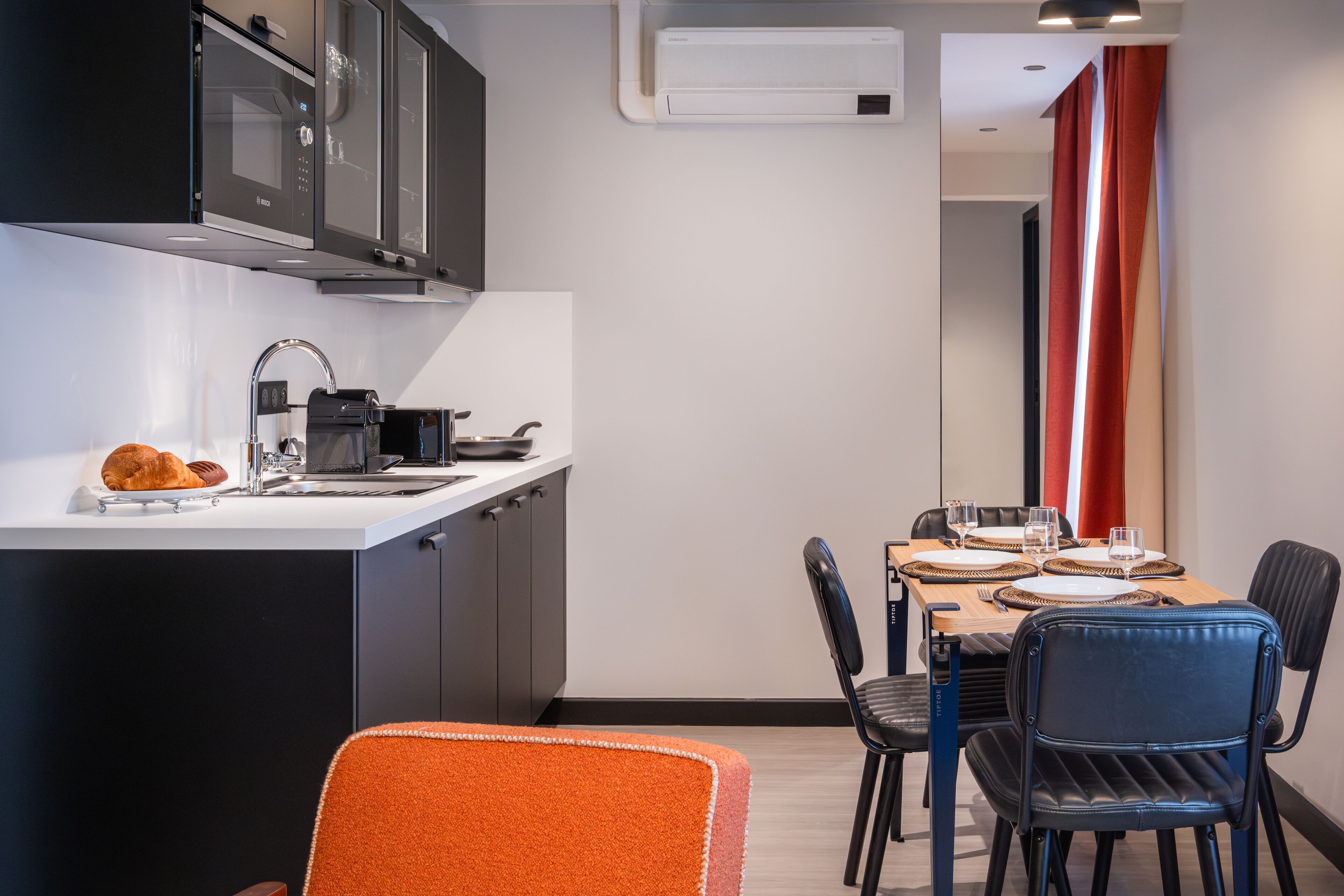 Una cucina compatta con forno a microonde, lavello e zona pranzo con tavolo apparecchiato per due.