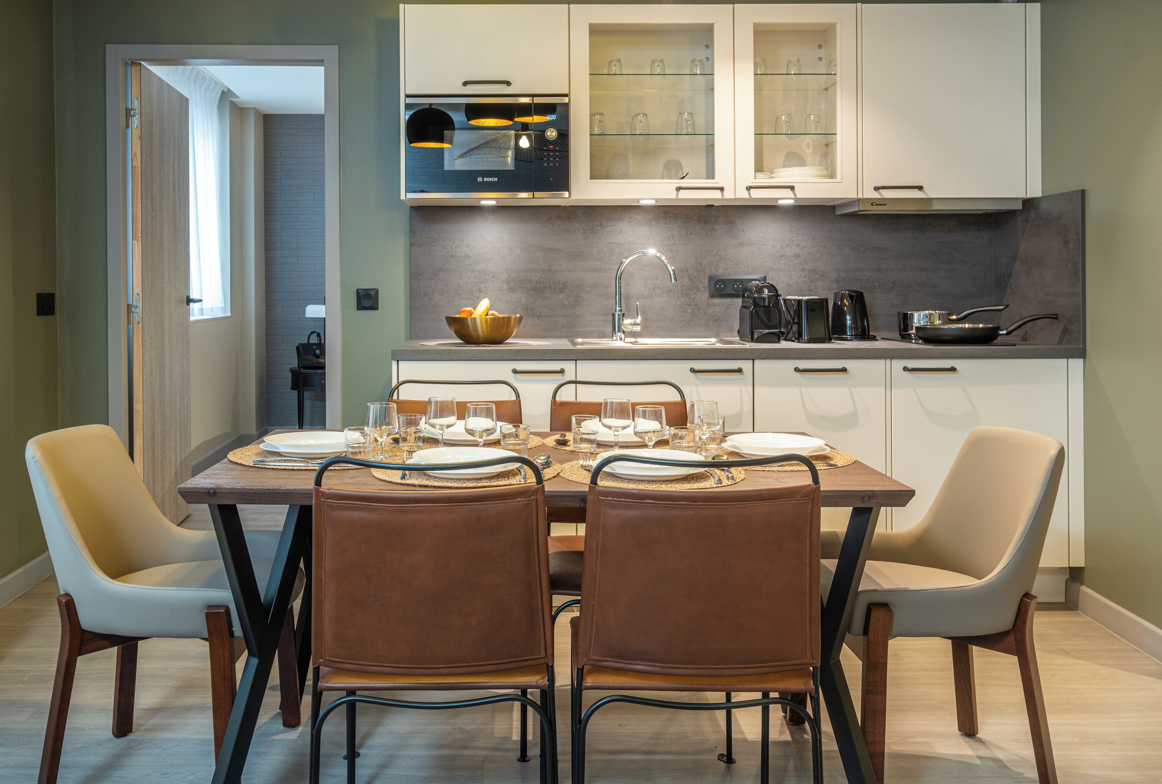 A modern kitchen with white cabinets, a Bosch microwave, and a dining area with a wooden table set for four.