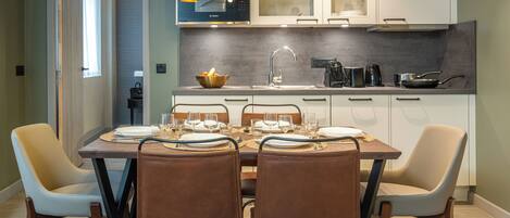 A modern kitchen with white cabinets, a Bosch microwave, and a dining area with a wooden table set for four.
