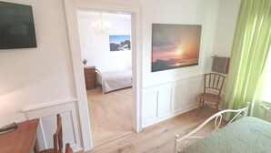 A bedroom with a bed, a chair, a painting, and a hallway leading to another room. - Gertrud Schlössli (St. Gallen)