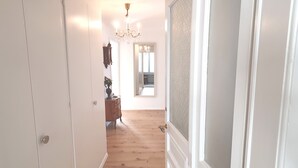 A hallway with wooden flooring, a mirror, a dresser, and a chandelier. - Gertrud Schlössli (St. Gallen)