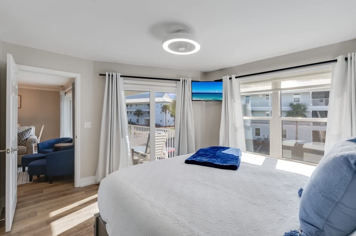 Habitación de hotel con cama, televisión y balcón con vista a edificios.