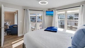 Quarto de hotel com cama, televisão e varanda com vista para edifícios.