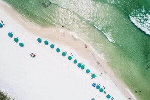An aerial view of a beach with a row of green umbrellas along the shoreline. - Newly Renovated | Beach | Pickleball | Pool (Santa Rosa Beach)