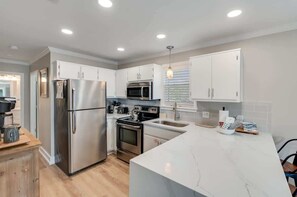 A modern kitchen with stainless steel appliances, white cabinetry, and a marble countertop. - Newly Renovated | Beach | Pickleball | Pool (Santa Rosa Beach)