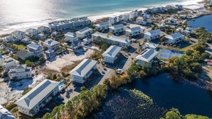 Vista aérea de um resort costeiro com vários edifícios, uma praia e uma área de água.