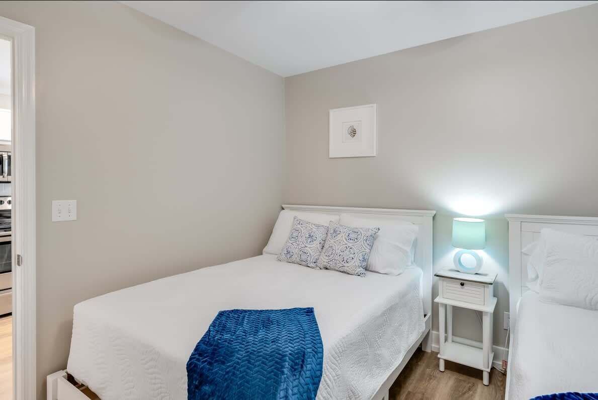 A bedroom with a bed, bedside tables, a nightstand with a lamp, and a wall-mounted picture.