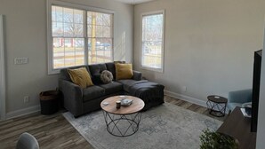 A living room with a gray sectional sofa, a round coffee table, and a ceiling fan.
