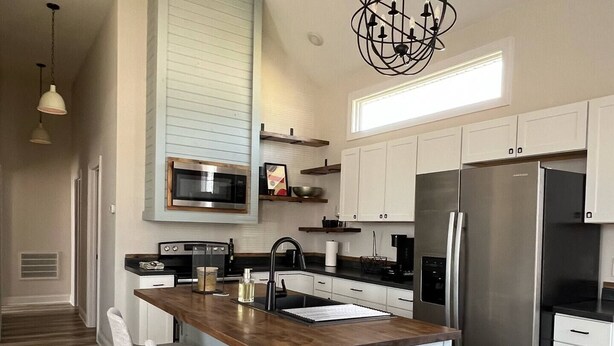 A modern kitchen with a central island, stainless steel appliances, and a pendant light.