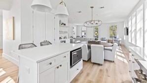 A spacious kitchen with a central island, white cabinetry, and pendant lighting. - New 4BR Home | Pool | Elevator | 8 Bikes (Rosemary Beach)