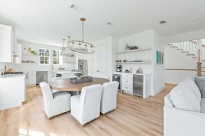 Una cocina moderna con armarios blancos, una mesa de comedor de madera y una araña.