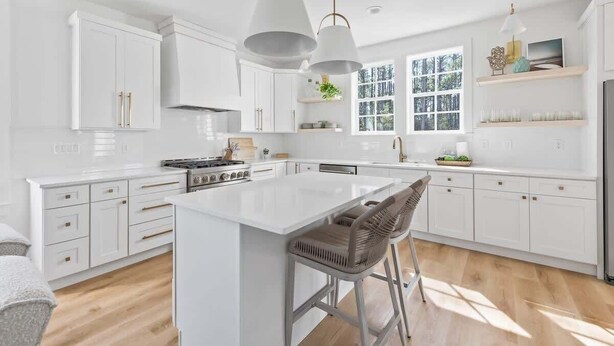 A modern kitchen with white cabinetry, a central island, and pendant lighting. - New 4BR Home | Pool | Elevator | 8 Bikes (Rosemary Beach)