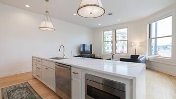 A modern kitchen with a large island, stainless steel appliances, and pendant lighting.