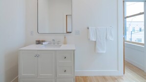 Ein modernes Badezimmer mit einem weißen Waschtisch, einem großen Spiegel und einem Handtuch an der Wand.