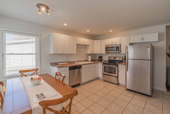 A modern kitchen with white cabinets, stainless steel appliances, and a dining area with a wooden table and chairs. - This house is a 2 bedroom(s), 1 bathrooms, located in Marion, IN. (Marion)
