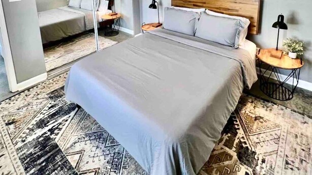 A bedroom with a bed, a ceiling fan, a nightstand, and a mirror.