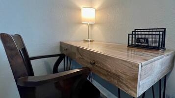 Un bureau d’angle avec une lampe, une chaise et un présentoir à lettres.
