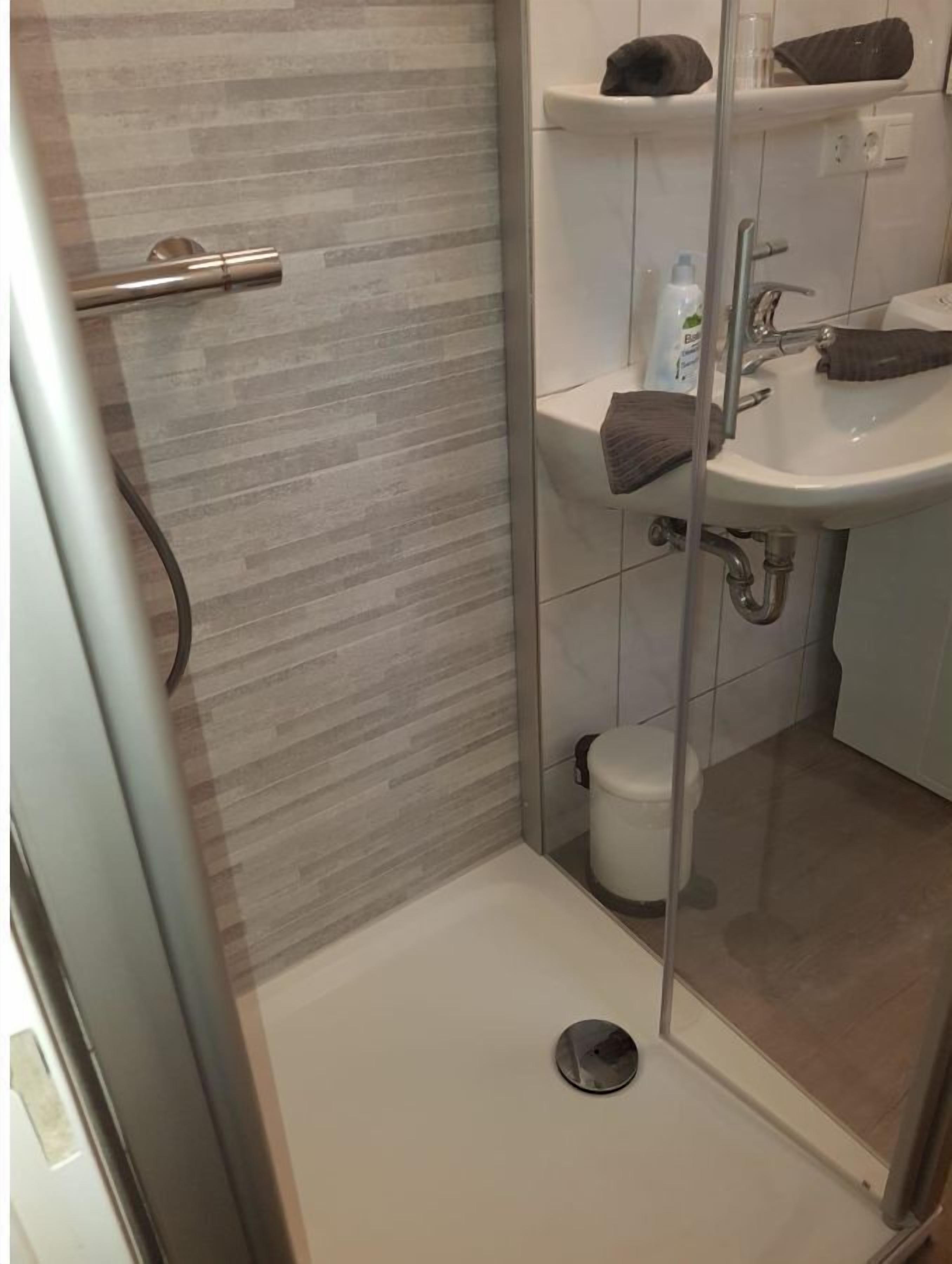 A modern bathroom with a glass shower enclosure, a toilet, and a sink with a towel on the counter.