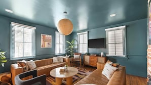 A spacious living room with a large sofa, a coffee table, and a television. - Ivy Manor | DT Oasis + Carriage House! (Charleston)