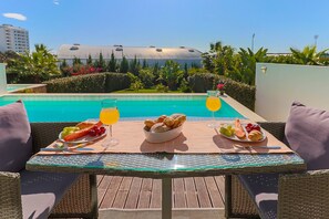 Enjoy a peaceful breakfast or snack in our serene outdoor dining area, surrounded by lush greenery and a pool.