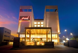 Un hôtel au design moderne, avec une enseigne imposante portant le mot « Grand » et une entrée bien éclairée.
