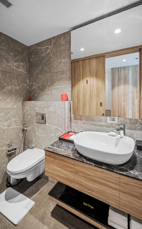 Un baño moderno con tocador de mármol, lavabo blanco y retrete.