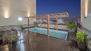 A rooftop pool area with a wooden deck, a small pool, and potted plants. - Grand Vijayawada by GRT hotels (Vijayawada)